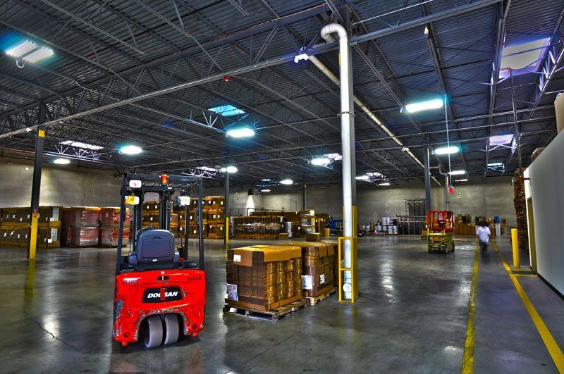 A red forklift is parked in a large warehouse.