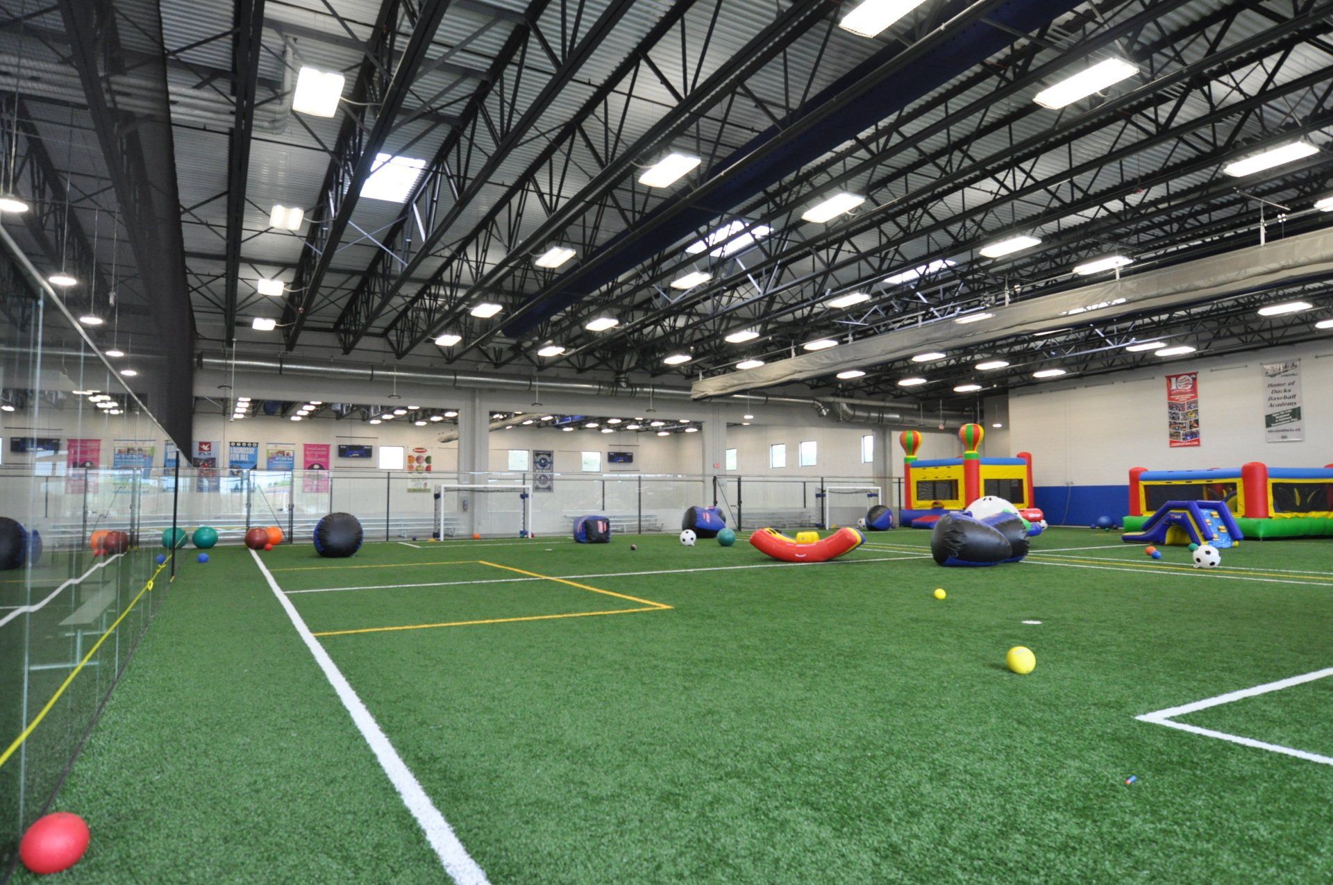A large indoor soccer field with balls and bouncy houses.