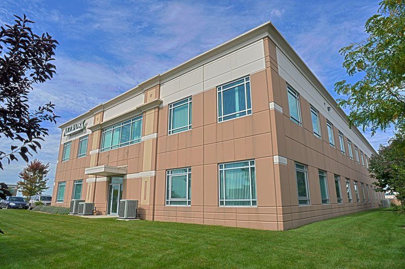A large building with a lot of windows is sitting on top of a lush green field.
