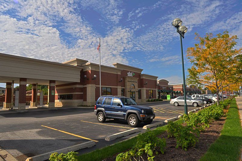 A blue jeep is parked in front of a brick building.
