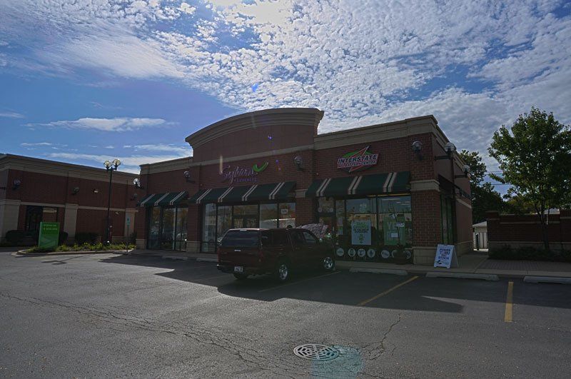 A red truck is parked in front of a brick building.