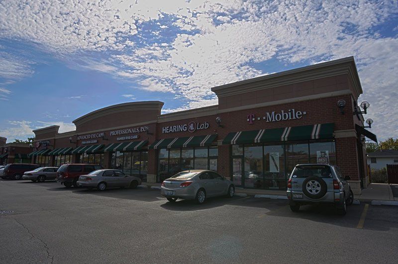 A row of cars are parked in front of a t mobile store.