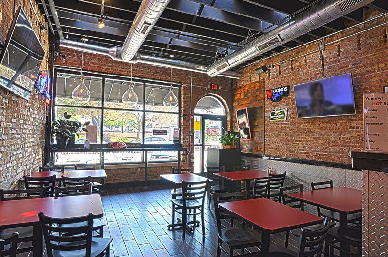 A restaurant with tables and chairs and a television on the wall.
