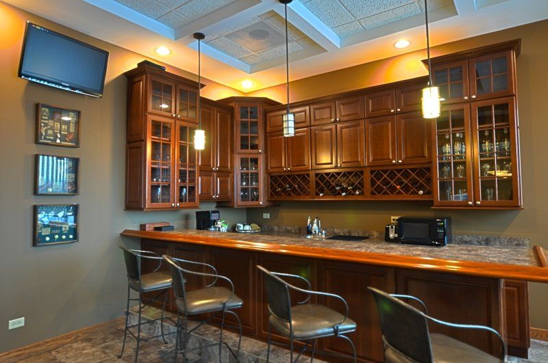 A kitchen with a bar and chairs and a television on the wall.