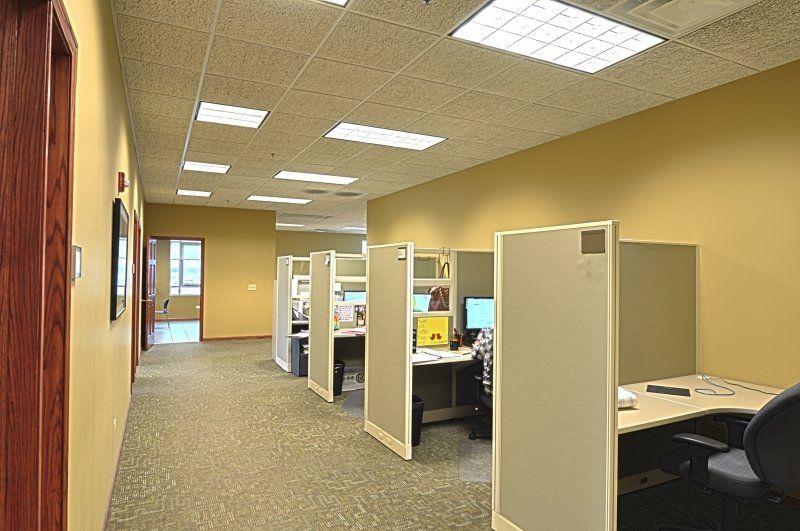 A woman is sitting at a desk in a cubicle in an office