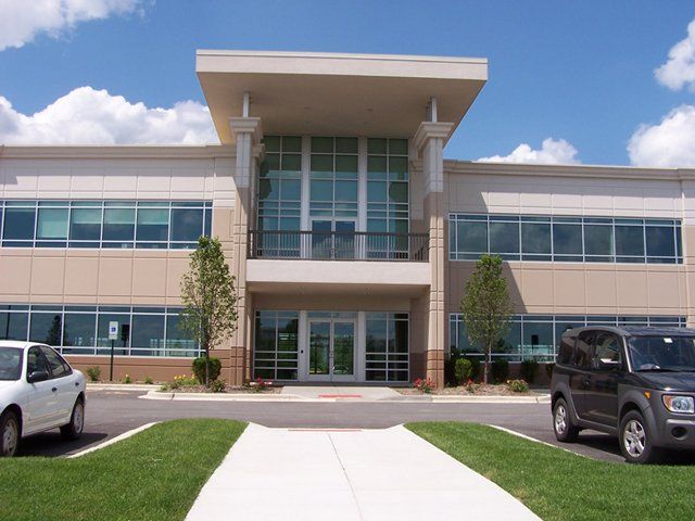 Two cars are parked in front of a large building