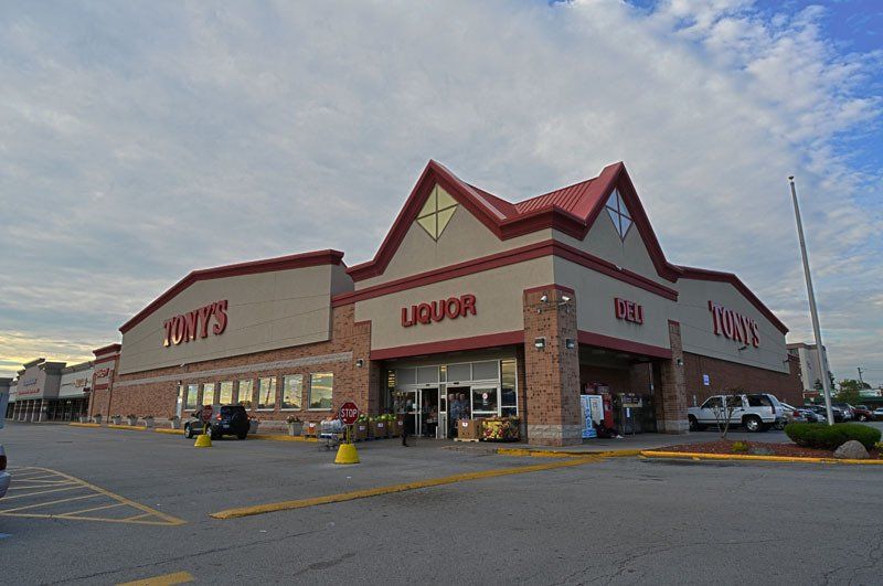 A liquor store with a red roof and a parking lot in front of it.