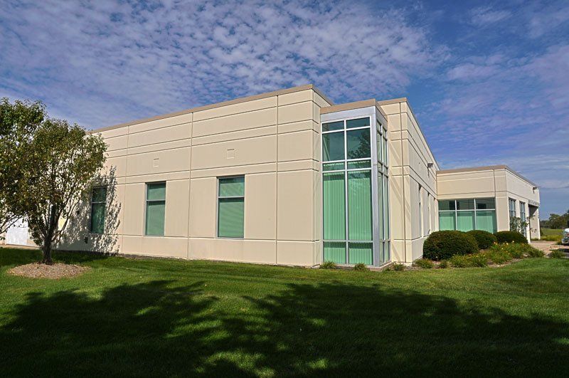 A large white building with lots of windows is sitting on top of a lush green field.