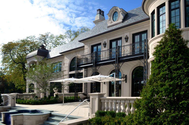 A large house with a pool and umbrellas in front of it.
