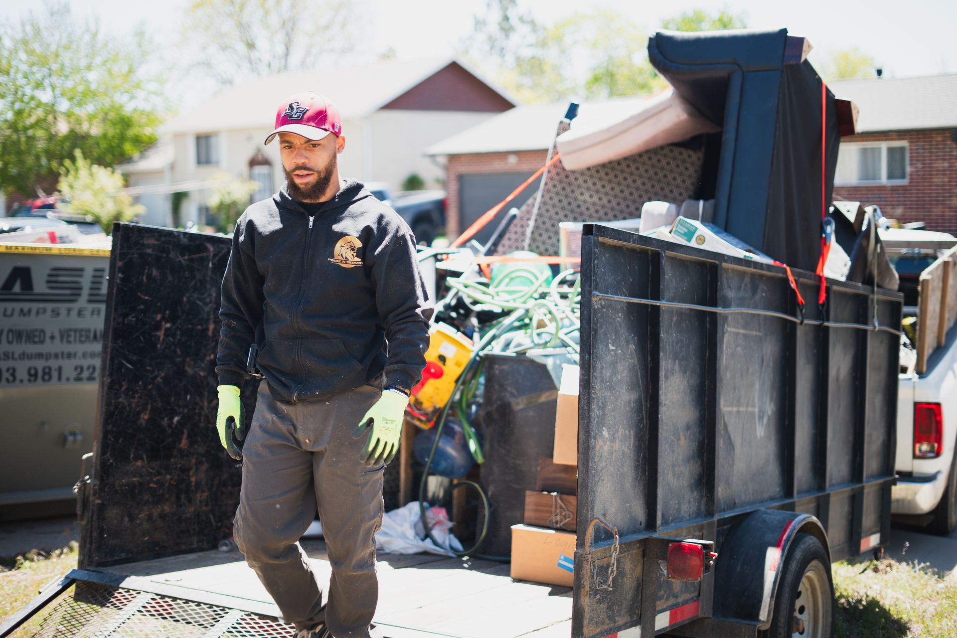 A man is standing next to a trailer full of trash.