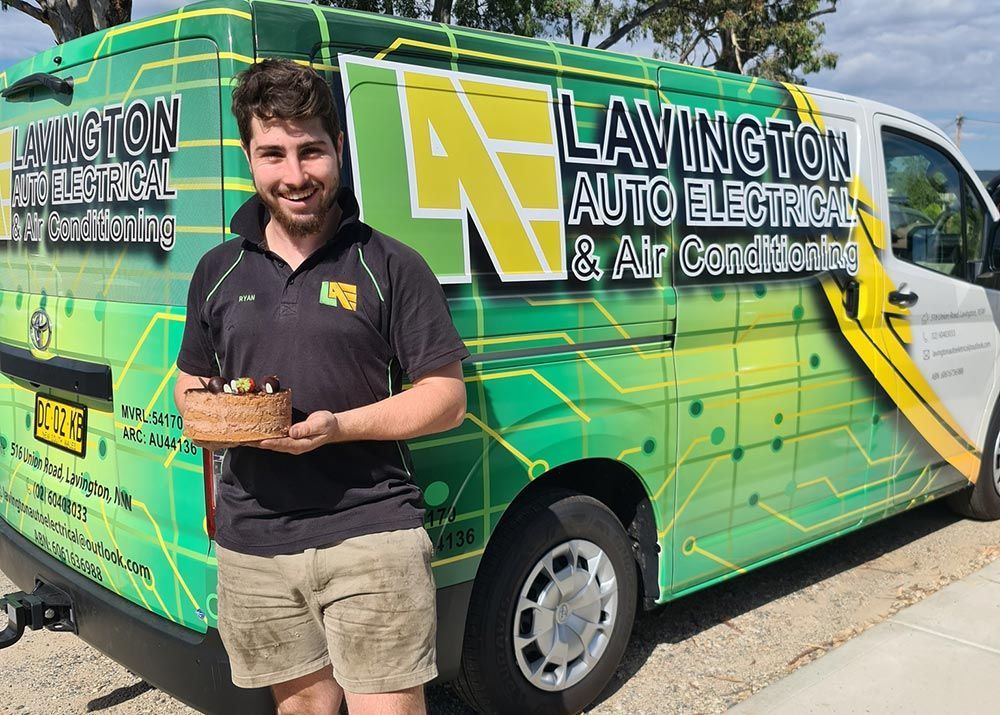 Man Holding Cake in Front of Van — Lavington Auto Electrical in Lavington, NSW