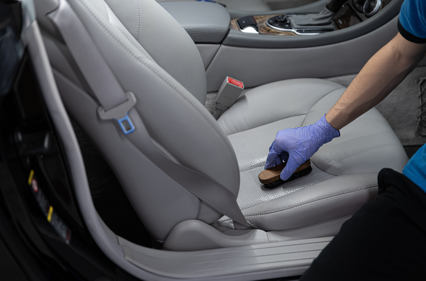A person is cleaning the seats of a car with a brush.