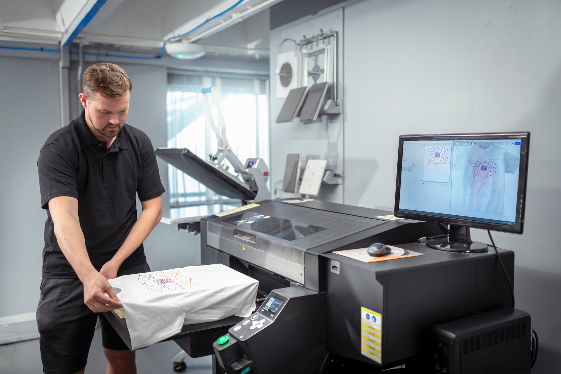Worker printing t-shirt in embroidery and fabric printing factory.