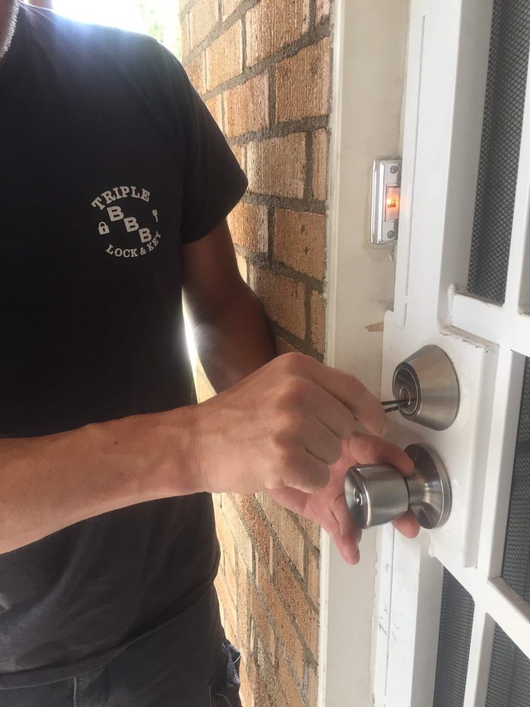 A man wearing a purple shirt is opening a door