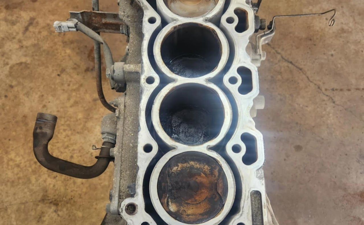 Engine cylinder head with four circular openings, showing wear and discoloration | Lucky Autolabs