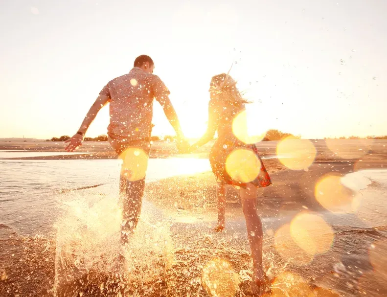 A Couple Running Down A Beach Holding Hands — Serene Therapy with Lana In Paddington, NSW