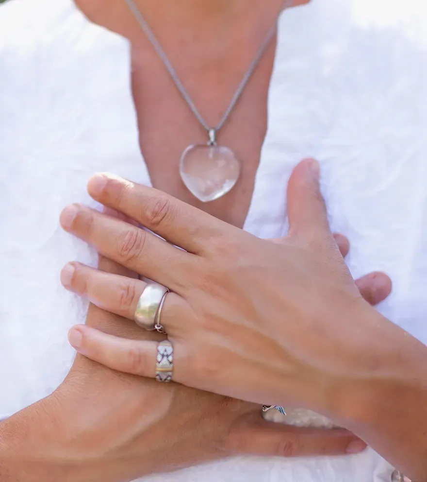 Hands on chest over a white shirt, wearing rings and a heart pendant necklace. — Serene Therapy with Lana In Paddington, NSW