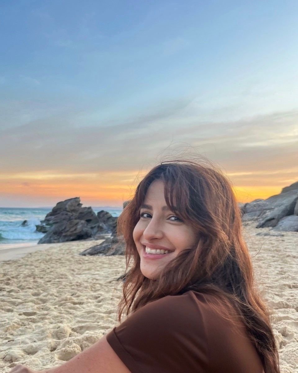 Ocean waves crashing against a rocky shore, houses on a hill in the distance, bathed in golden light. — Serene Therapy with Lana In Paddington, NSW