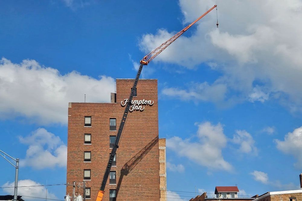 A white truck is parked in the woods next to a house.