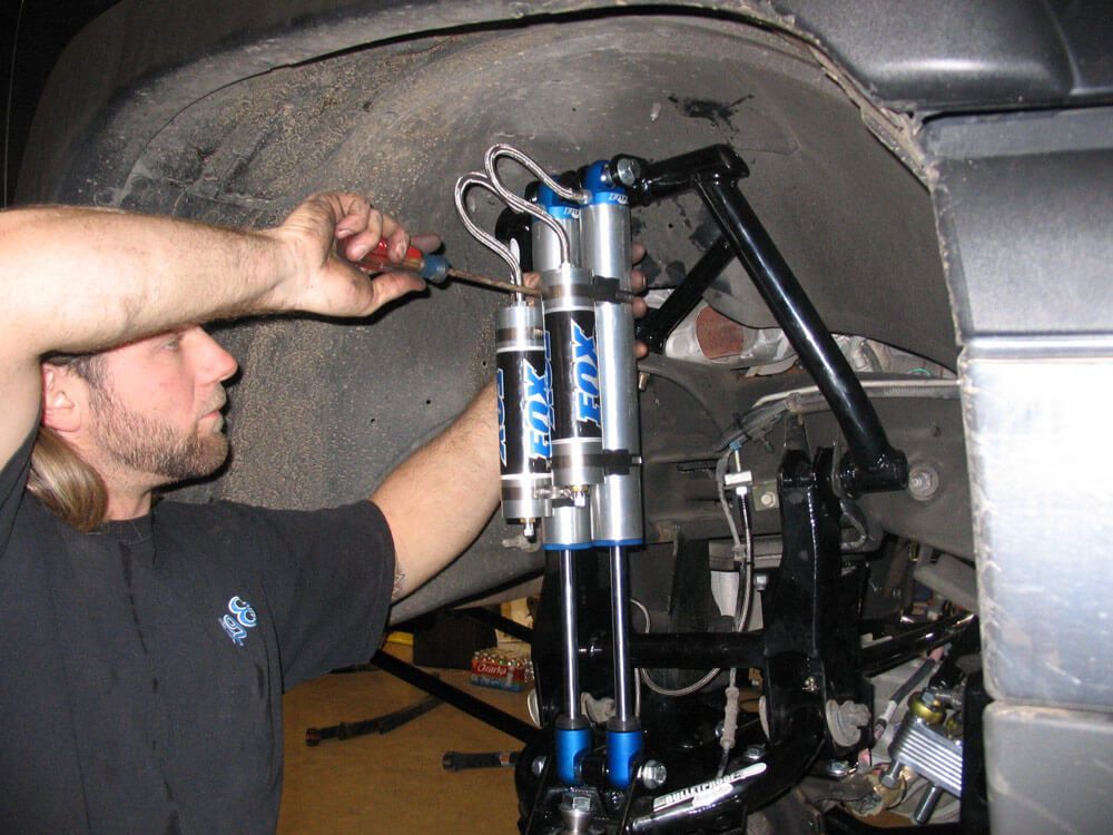 A man is working on a vehicle with fox shocks