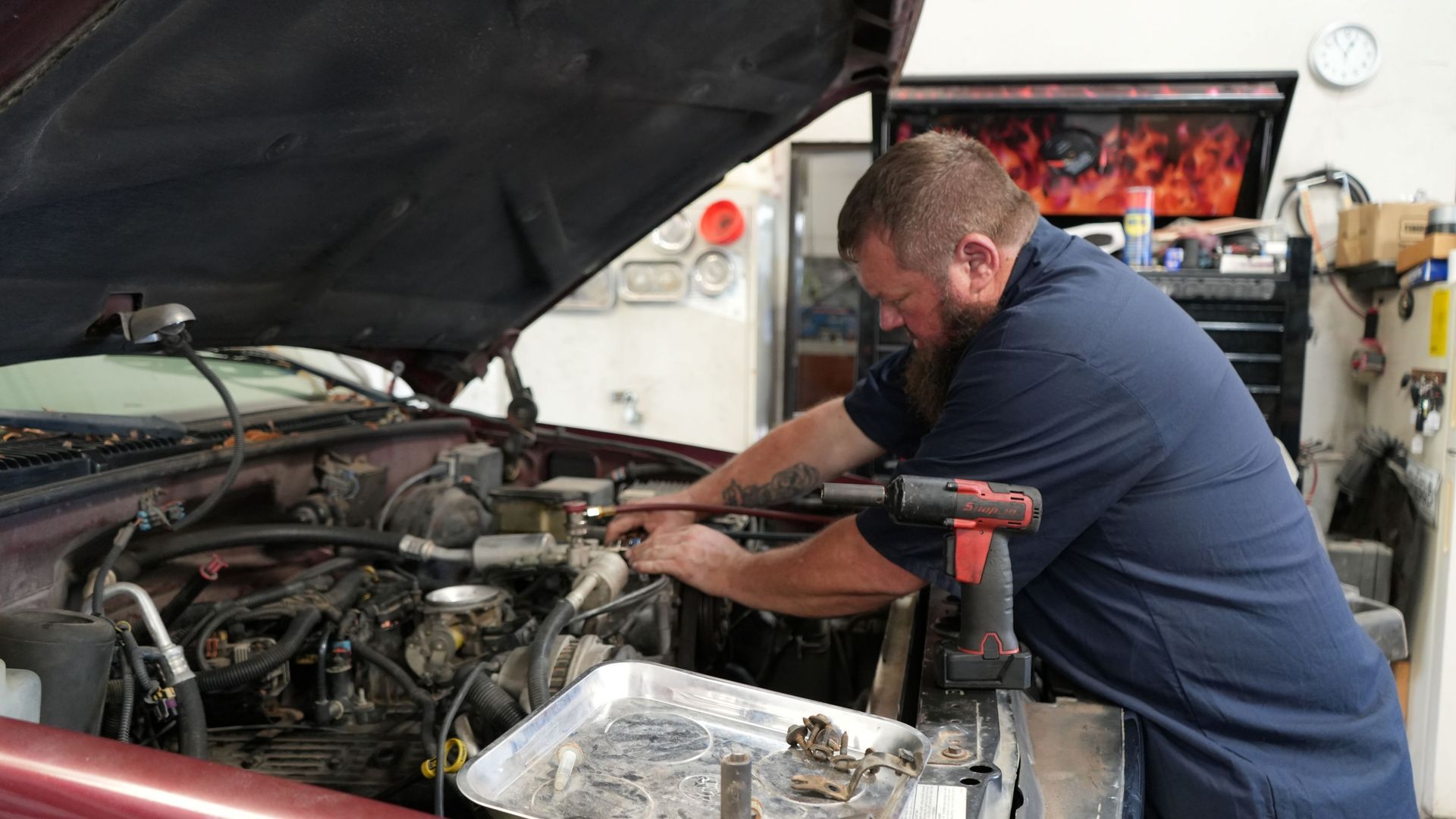 A man is working on the engine of a car in a garage.