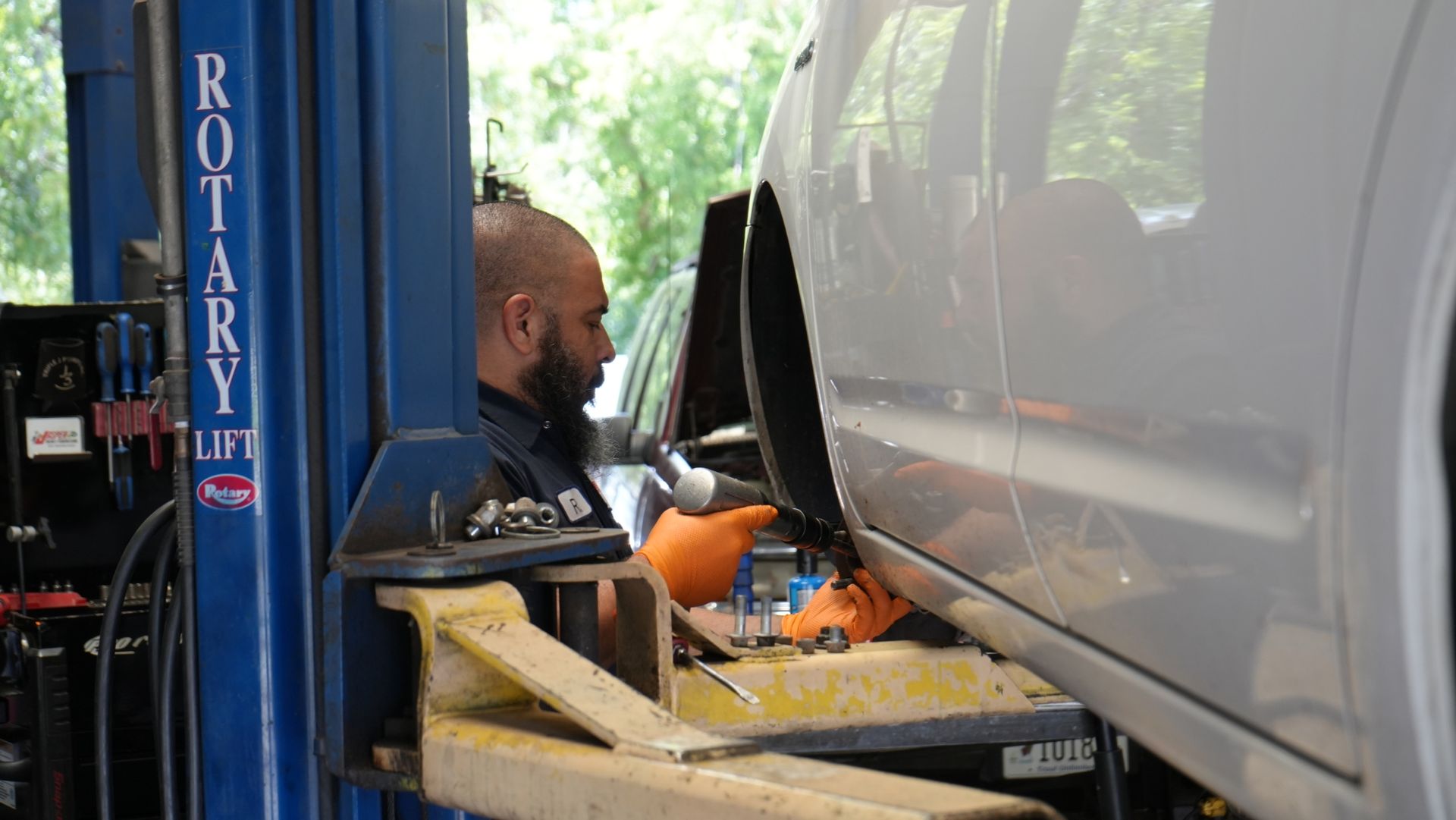 A man is working on a car on a lift in a garage.