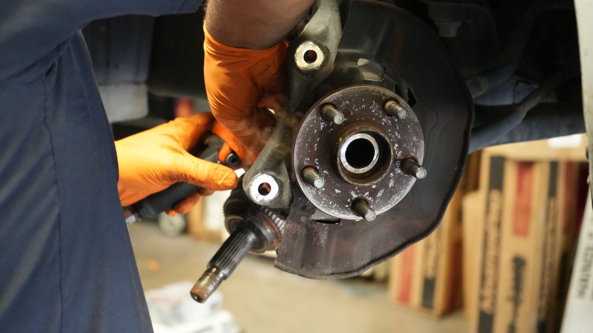 A man wearing orange gloves is working on a car wheel.
