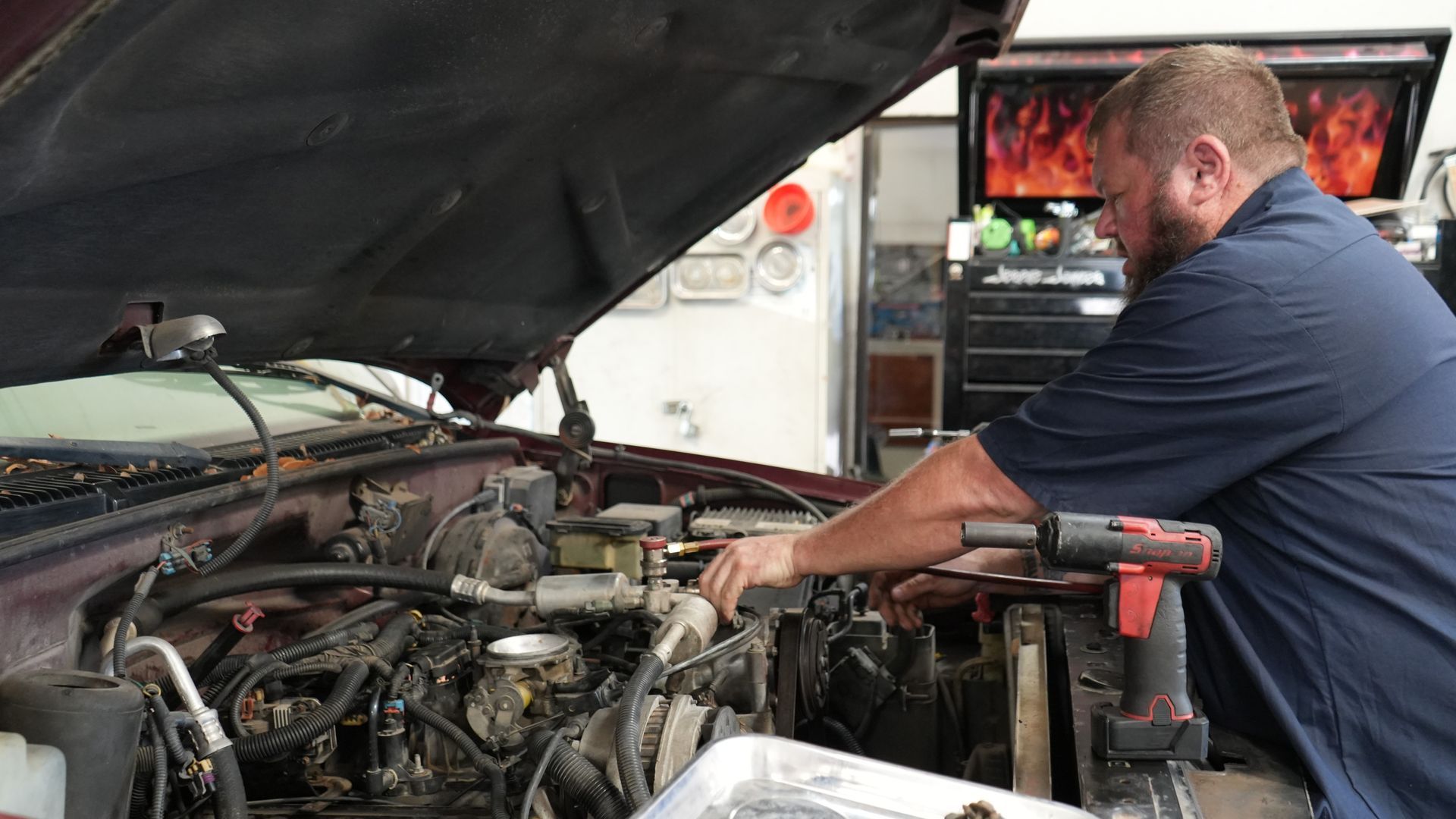 A man is working on the engine of a car in a garage.