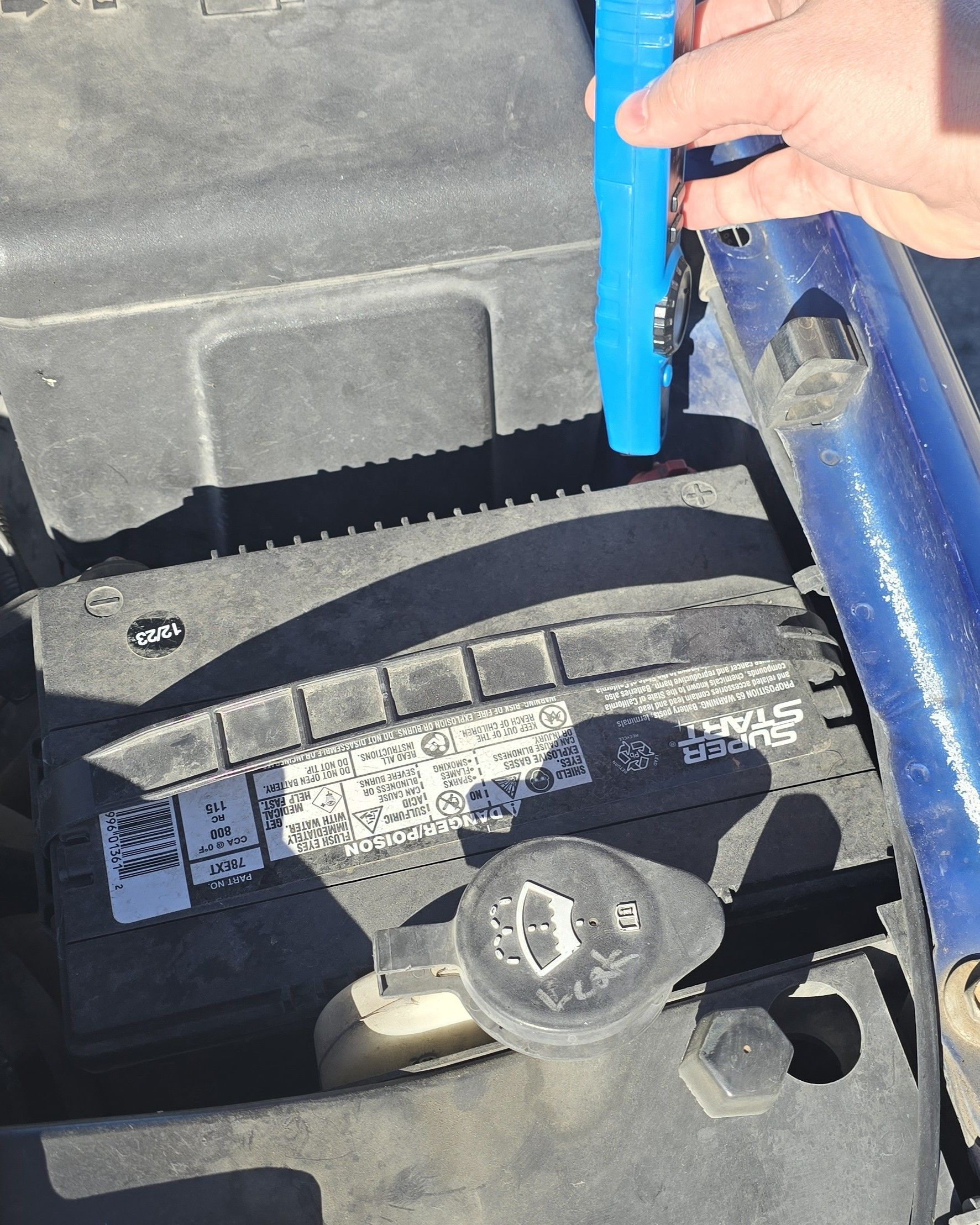 A person is opening the hood of a car to check the battery