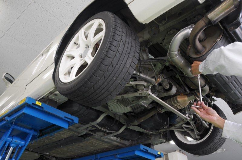a man is working on the underside of a car with a wrench .