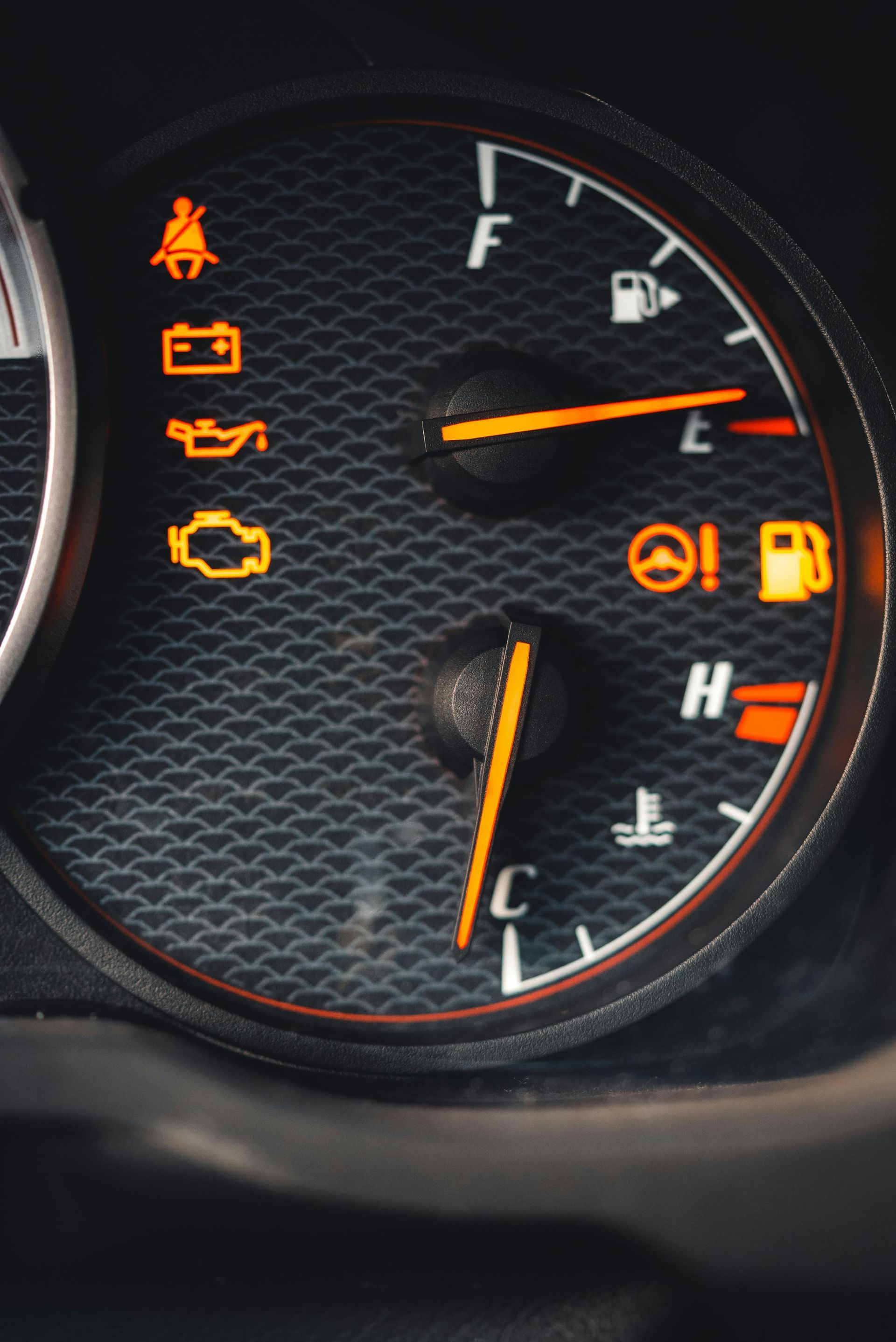 Car dashboard with illuminated warning lights, including seatbelt, battery, and low fuel indicator.