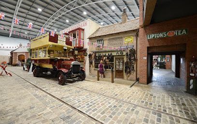Indoor display of a vintage street scene with an old bus, shops, and a person standing in front.