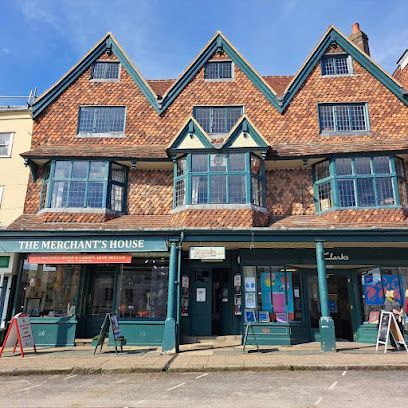 The Merchant's House, brick building with green trim and shop fronts, blue sky overhead.