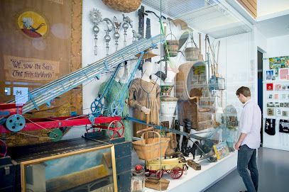 A man looks at a display case filled with antique tools and objects in a museum.