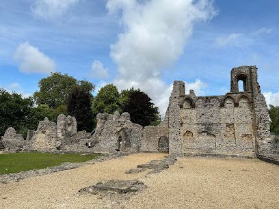 Ruined stone walls of a historic building under a partly cloudy blue sky.