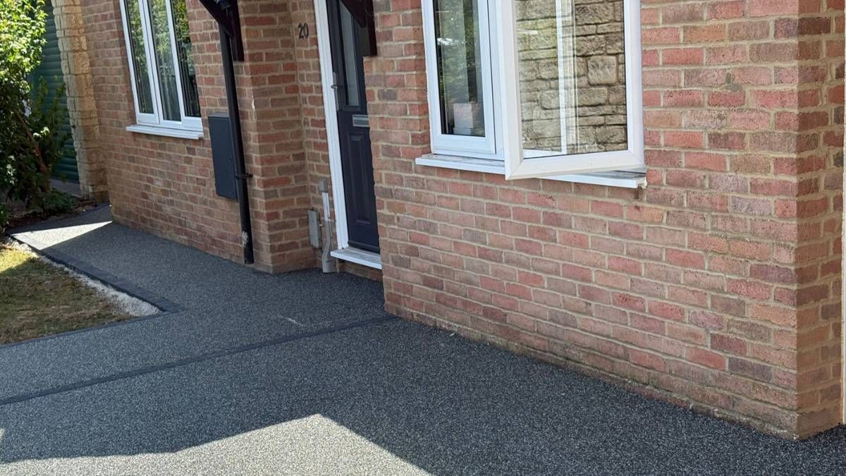 Brick house exterior with dark gray paved walkway leading to the front door.