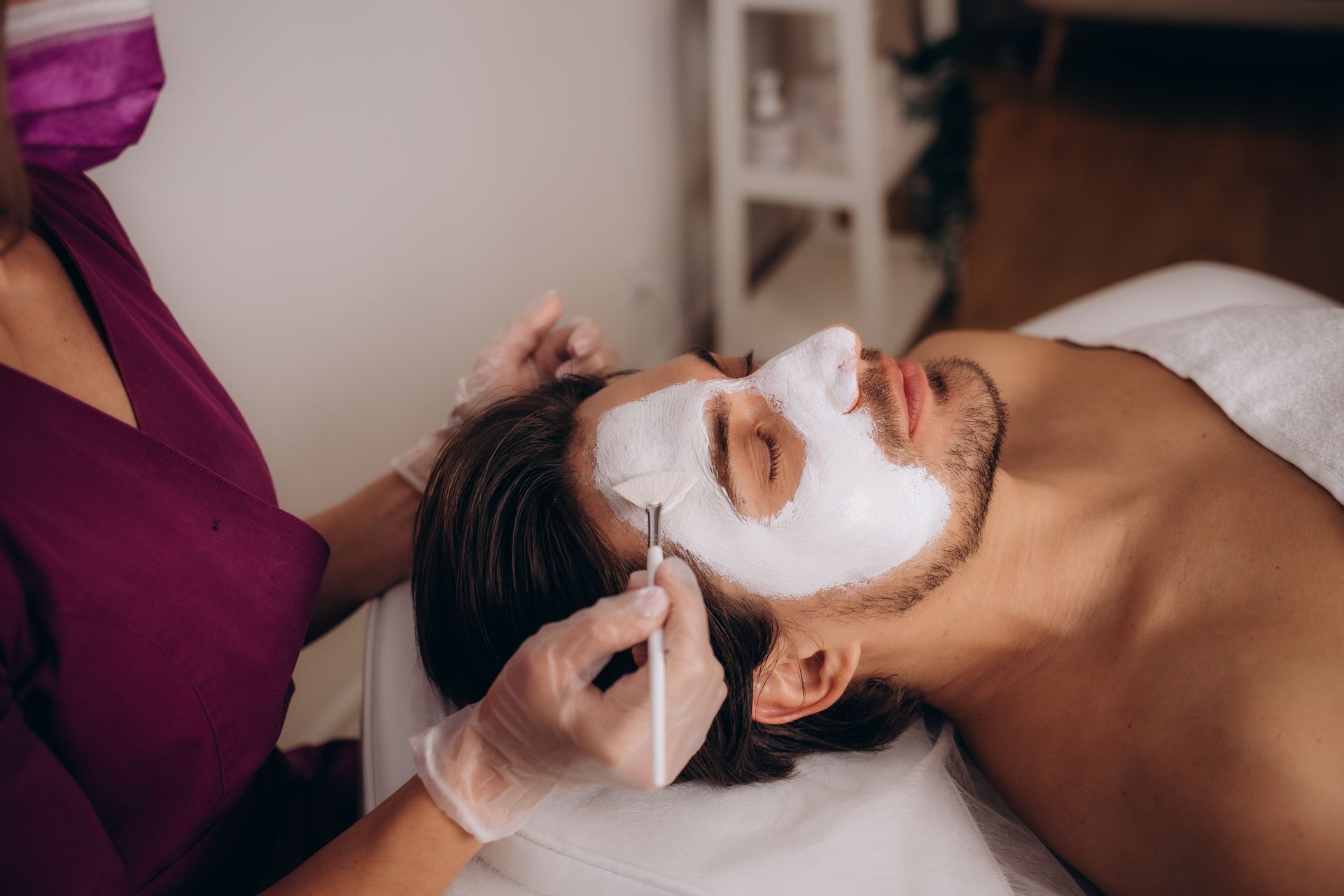 Tea-making scene: teapots, spoon with tea leaves, tea bag, honey dipper in a bowl, and lid on a dark surface.