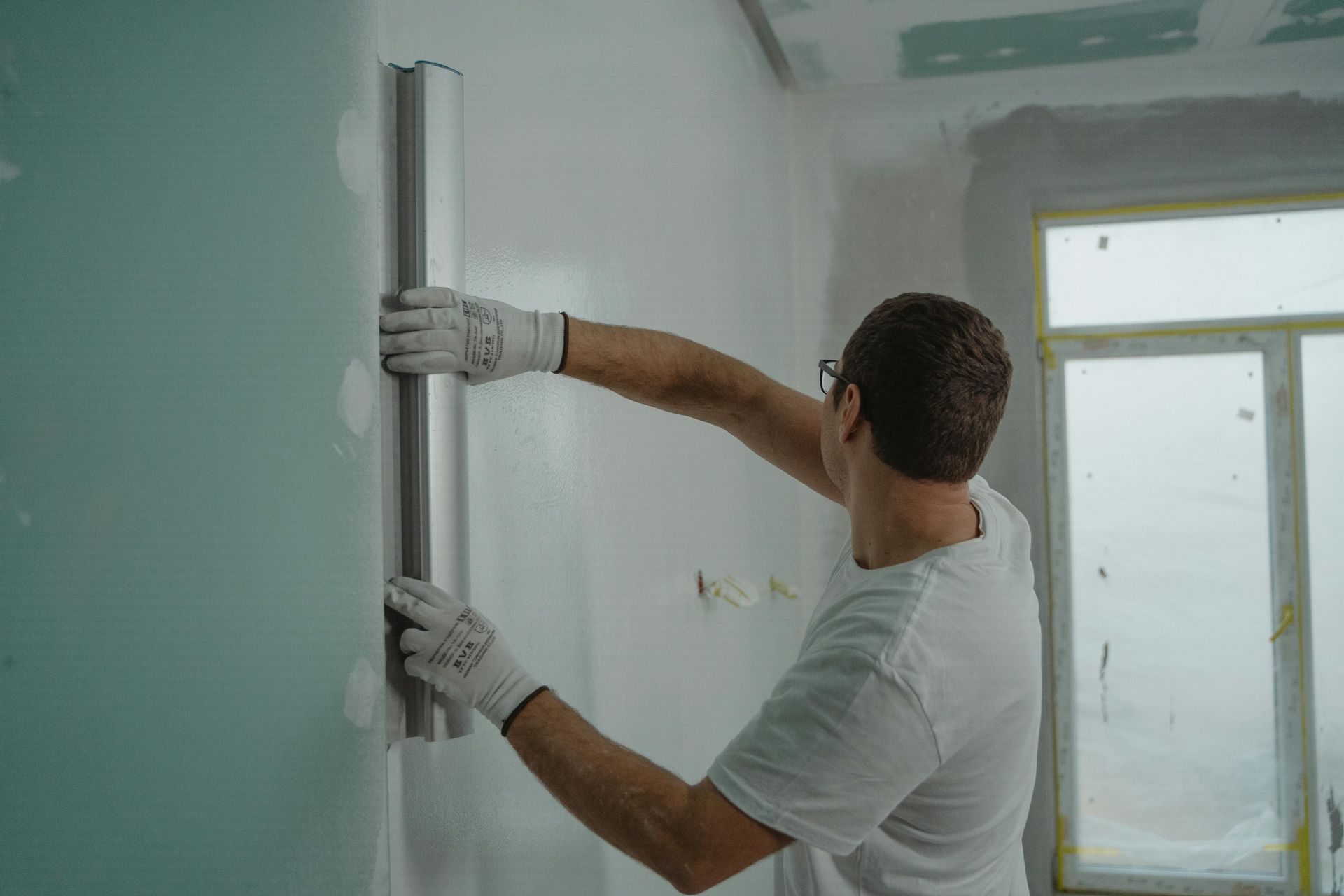 Person installing wall insulation in a room during renovation