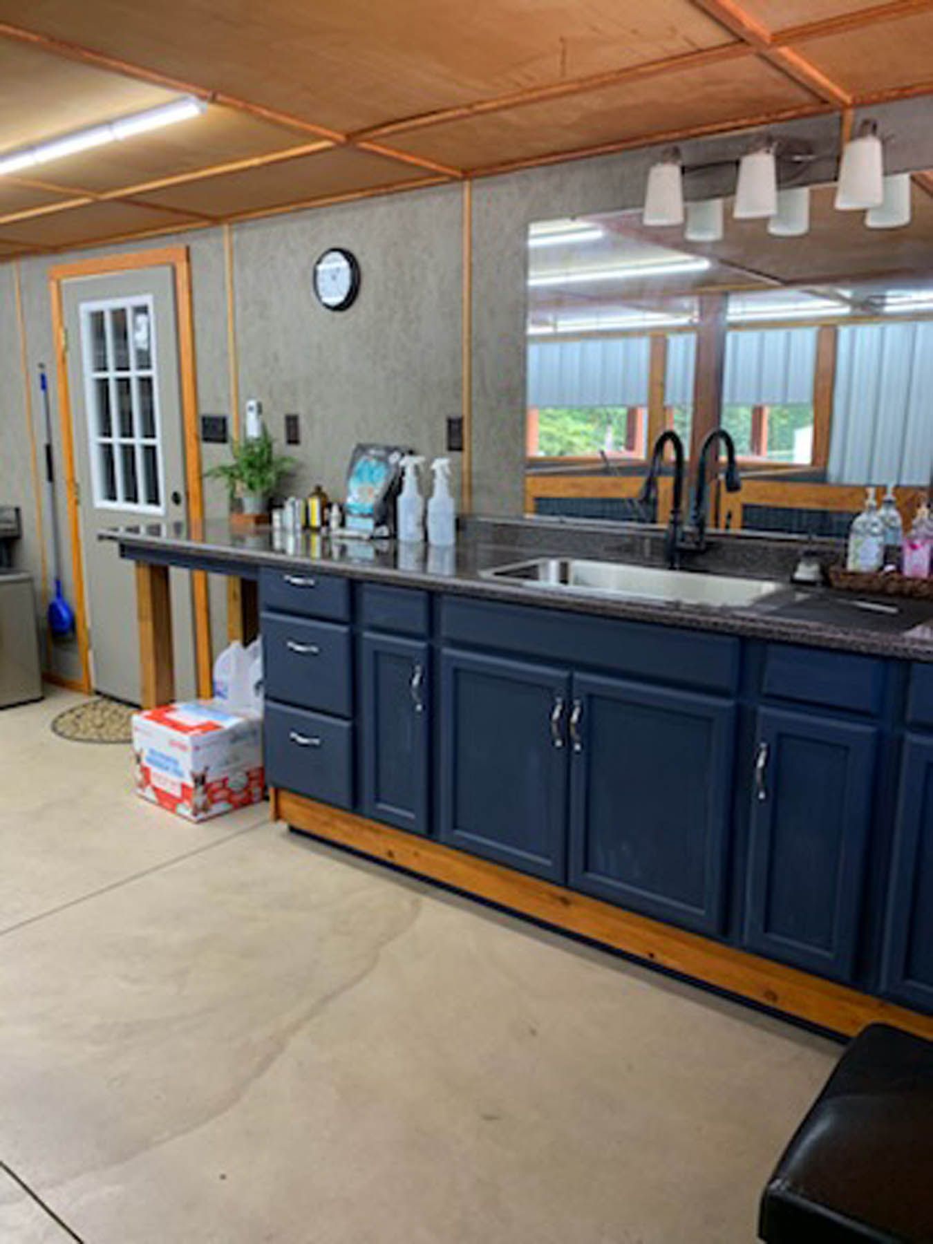 Kitchen with blue cabinets, dark countertop, and large sink. A door and window are visible.