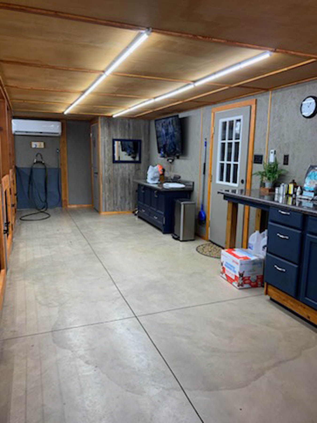 Interior with concrete floor, wood paneling, black cabinets, and appliances.