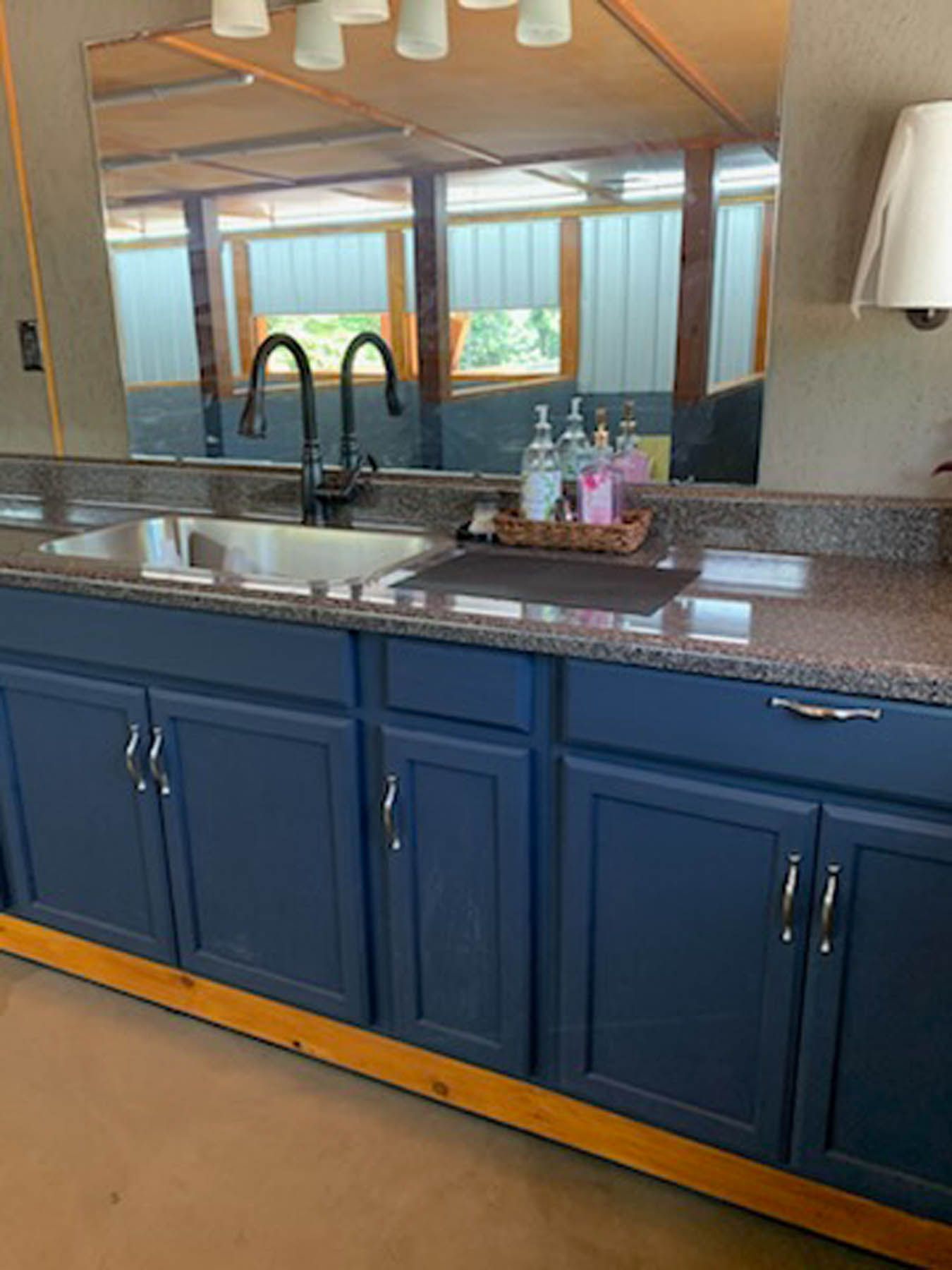 Navy blue bathroom vanity with granite countertop, sink, and mirror.