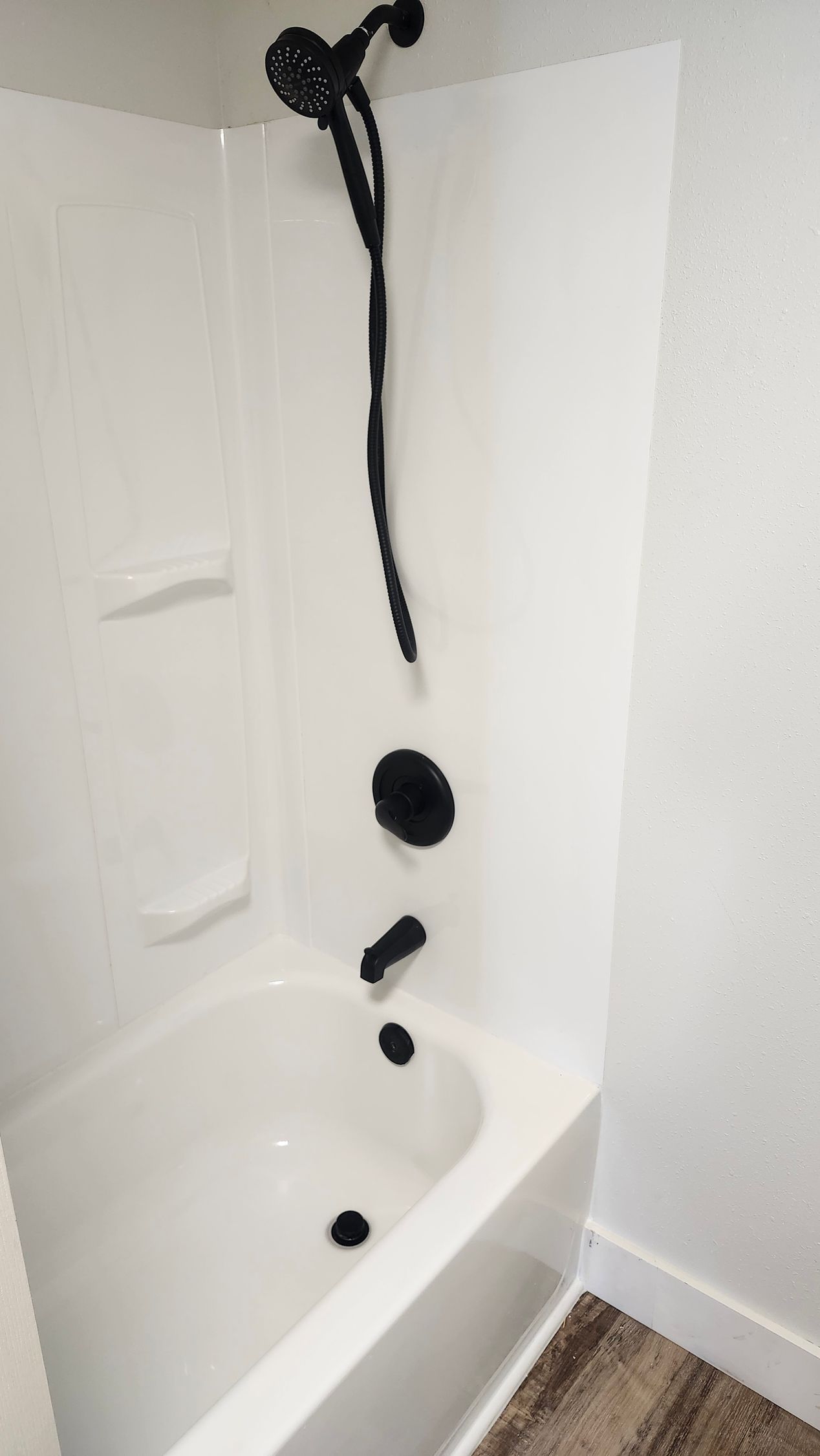 White bathtub with black shower fixtures in a white bathroom.