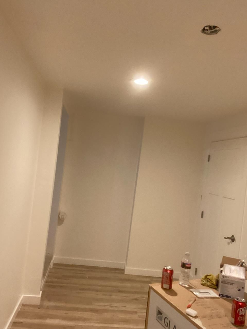 Interior with white walls, recessed lighting, doorway, and unfinished counter with objects.