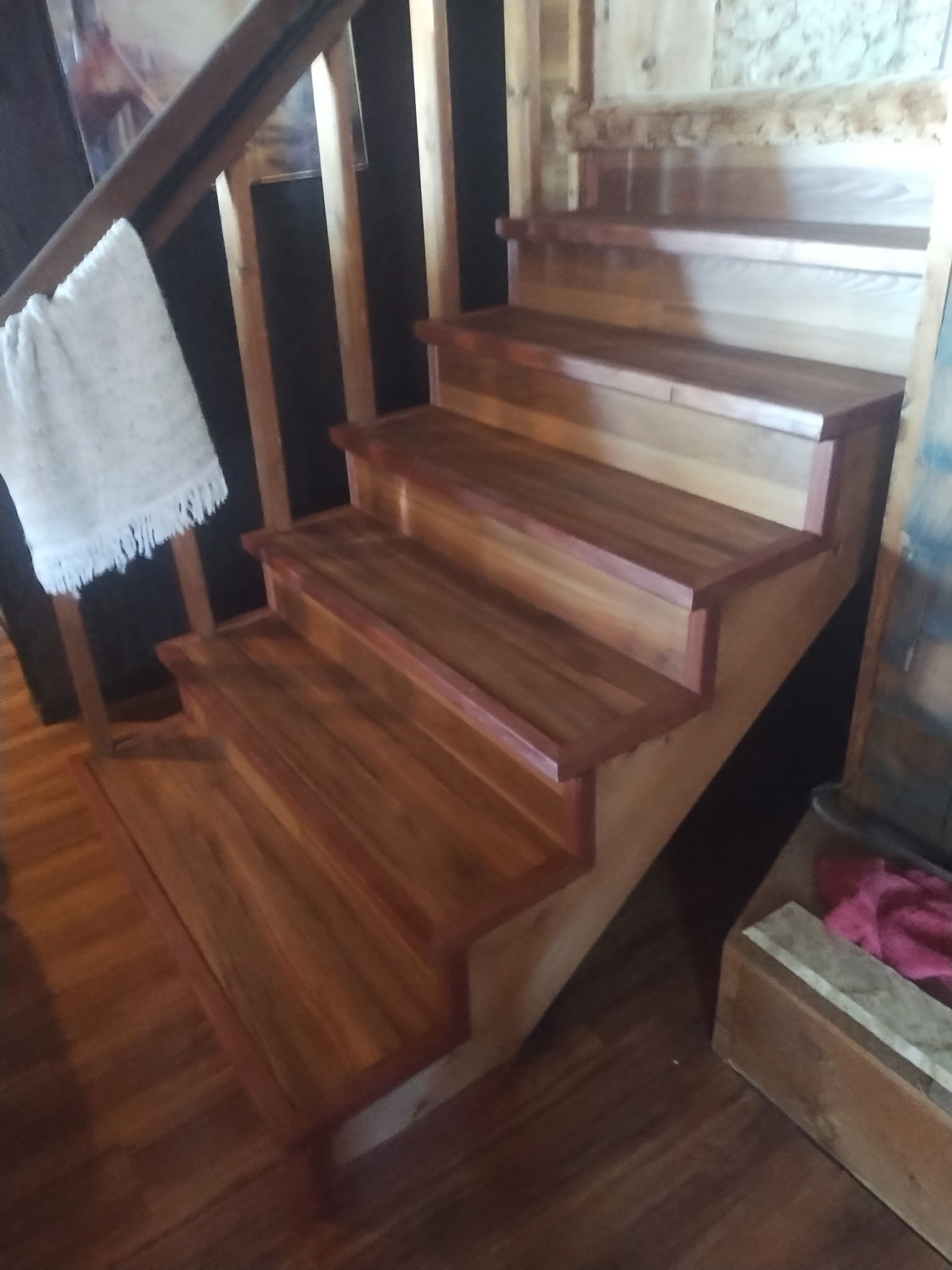 Wooden staircase with stained treads, risers, and handrail, inside a home.