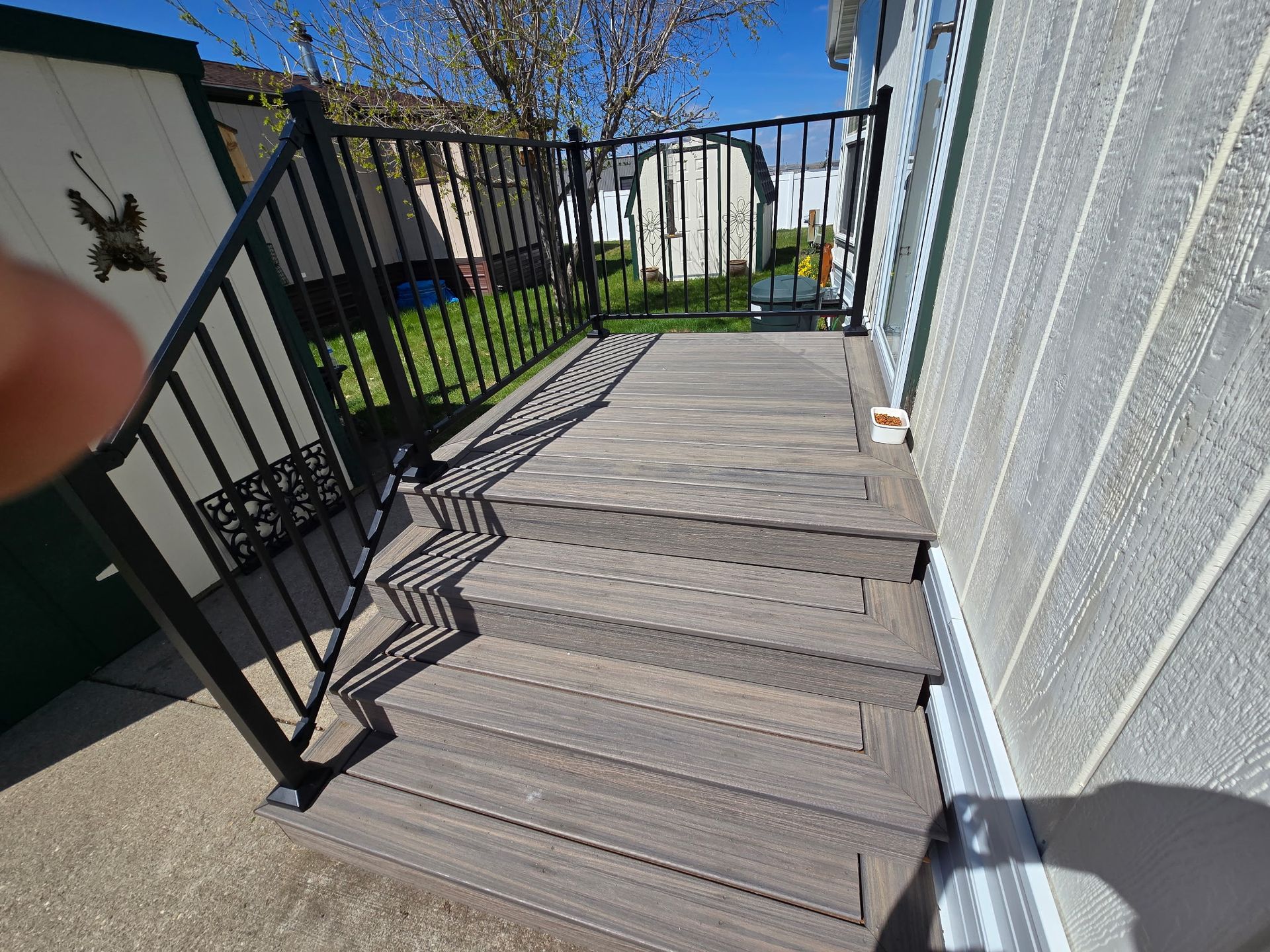 Composite deck with black railing and steps leading to a house.
