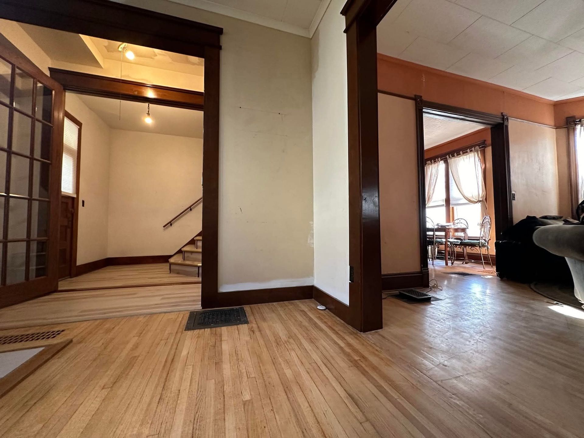 Hardwood floors, doorways, and stairs in a home with dark wood trim.
