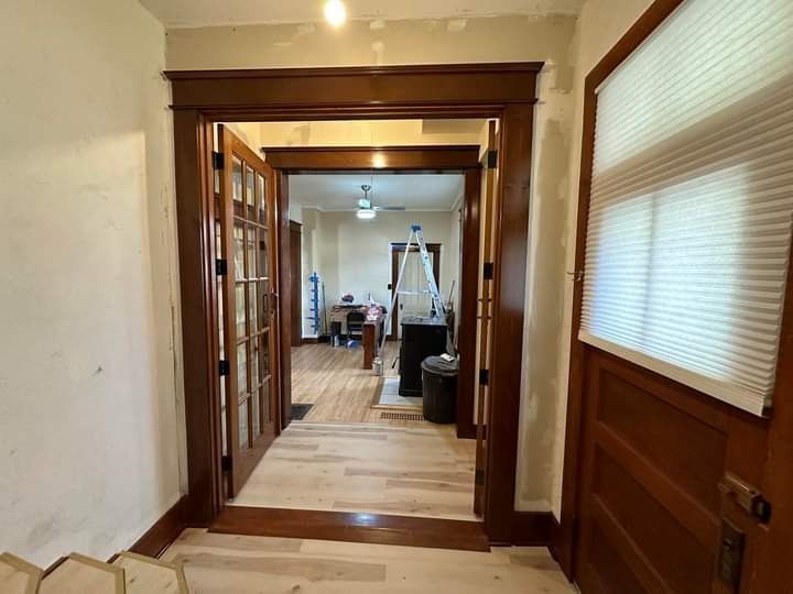 Hallway with wood trim and French doors leading to a room with furniture.