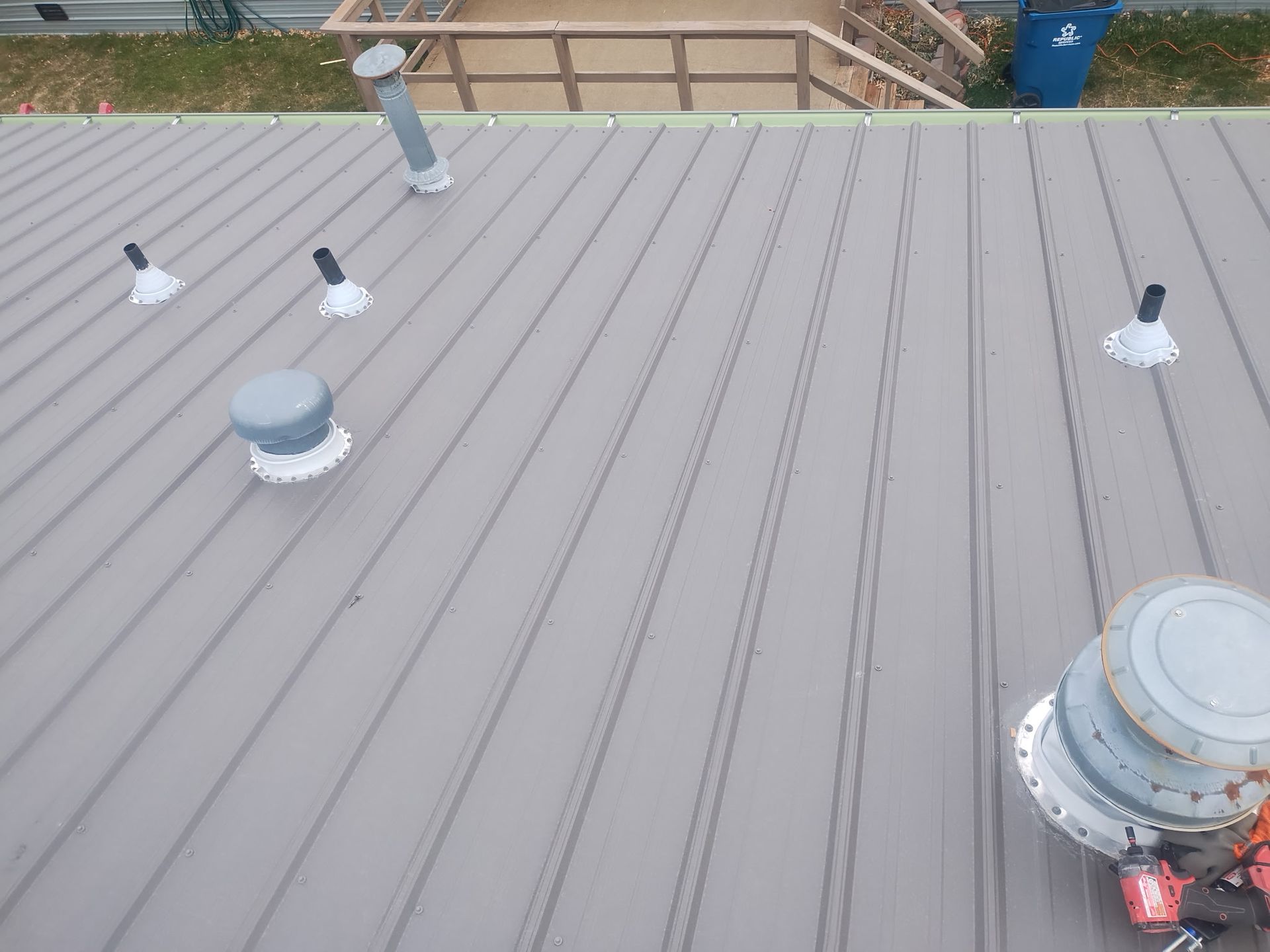 Gray metal roof with multiple vents and pipes.