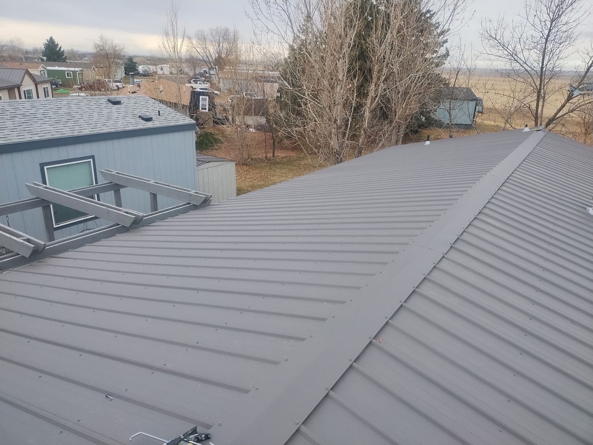 Gray corrugated metal roof with skylights, on a building with a residential setting.