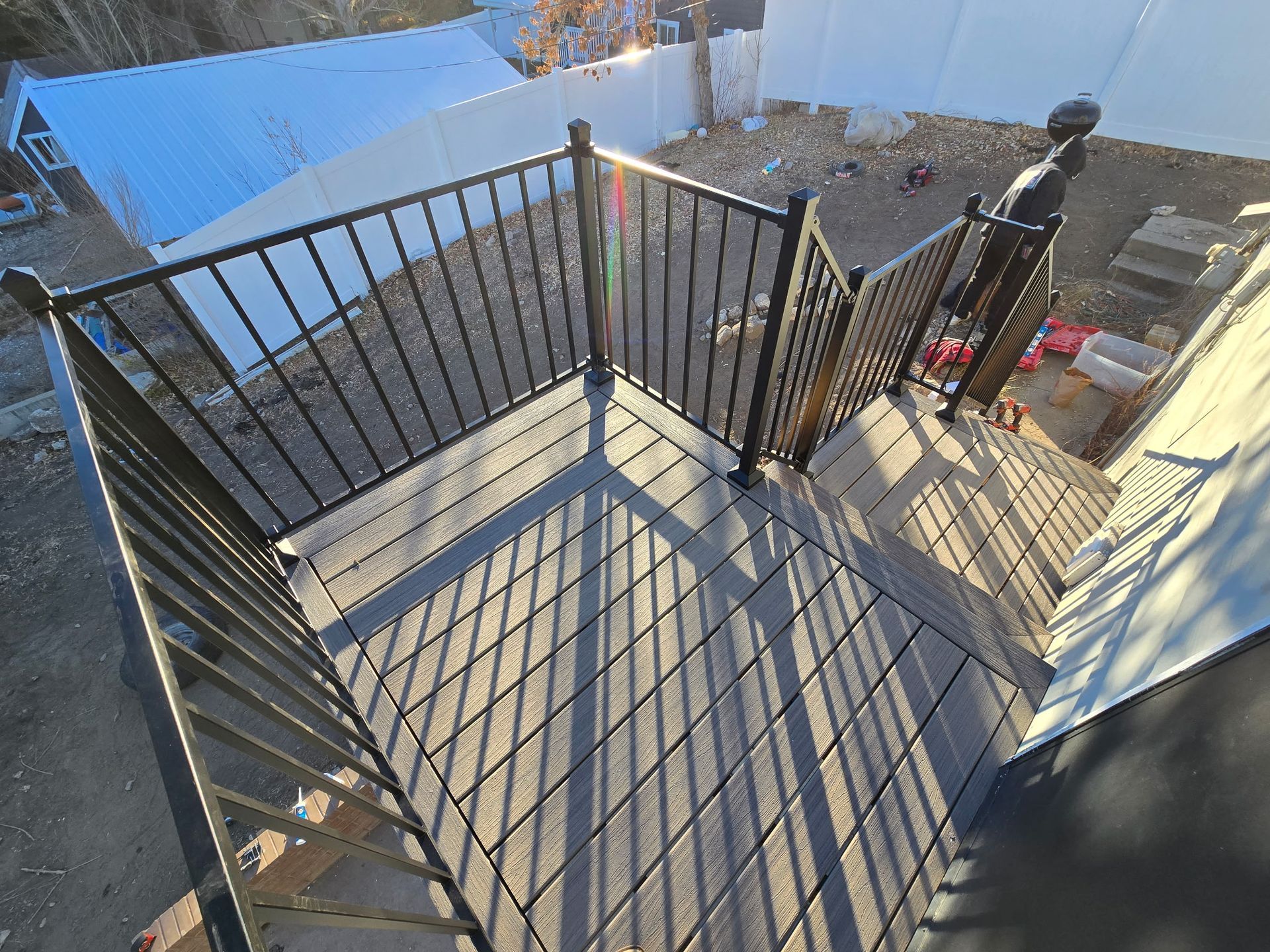 Deck with black railing, brown composite decking, and stairs leading down.